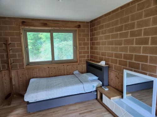 a small bedroom with a bed and a window at Samhyeongjebonggil Pension in Gangneung