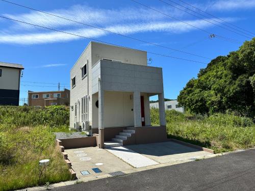 un petit bâtiment blanc sur le côté d'une route dans l'établissement 白浜貸別荘ss2-88, à Shirahama