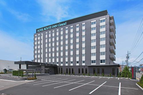 a large building with a parking lot in front of it at Hotel Route Inn Grand Nakano Obuse in Nakano