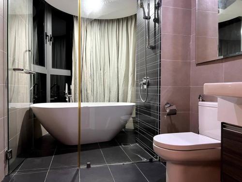 uma casa de banho com uma banheira grande e um WC. em Teega 12pax Cozy 4BR w Bathtub by Our Stay em Nusajaya