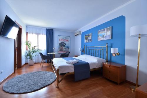 una camera da letto con pareti blu, un letto e un tavolo di Le Cinéma - Affittacamere a Formia
