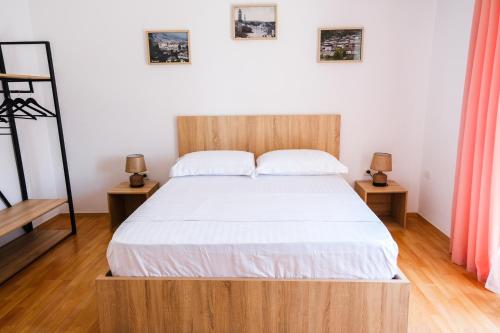 Bett mit einem Kopfteil aus Holz in einem Schlafzimmer in der Unterkunft Matias sweetest home in Tirana