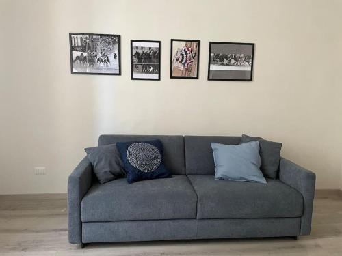 um sofá cinzento numa sala de estar com fotografias na parede em Casa del Riccio, Palio Siena em Siena