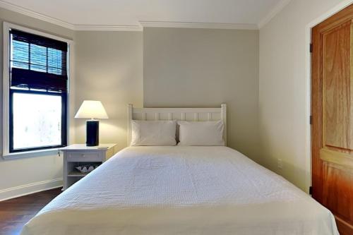 a bedroom with a white bed with a lamp and a window at Florencia #207 in Perdido Key