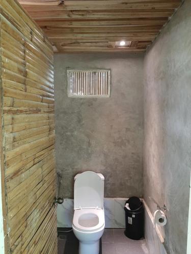 a bathroom with a toilet and a wooden wall at Cabanas de Nacpan Camping Resort in El Nido