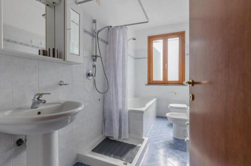 een badkamer met een wastafel, een toilet en een bad bij Casa Vacanza Rocchetti with Parking&Garden! in Porcari