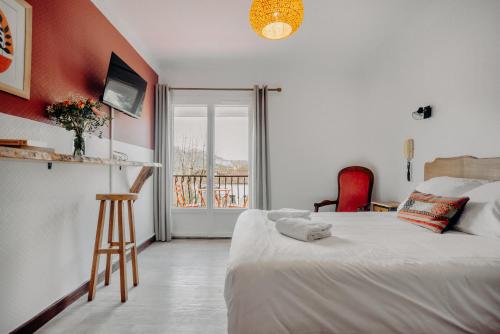 a bedroom with a white bed and a balcony at Logis Hôtel Restaurant Espelletenia in Larceveau-Arros-Cibits