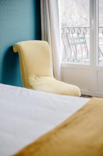 a yellow chair sitting in front of a window at Logis Hôtel Restaurant Espelletenia in Larceveau-Arros-Cibits
