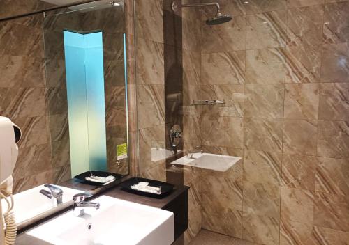 a bathroom with a sink and a shower with a mirror at King's Hotel Nagoya Batam in Nagoya