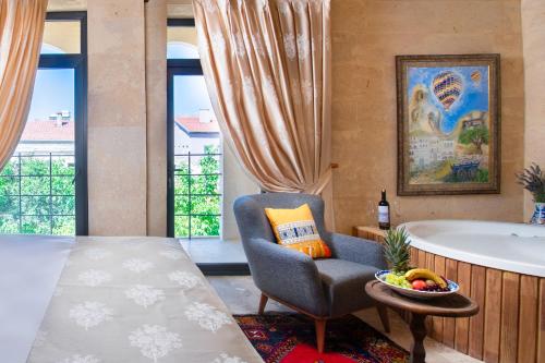 a bedroom with a bed and a chair and a tub at Cappadocia Pyramid Stone House in Uchisar
