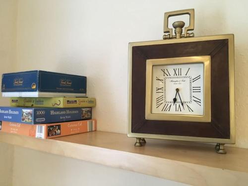 une horloge assise sur une étagère avec des livres dans l'établissement Caledonian - Charming Central 1 Bed Flat, à Édimbourg