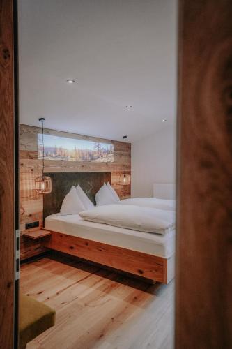 a bedroom with a large white bed with a mirror at Frühstückspension Friedheim in Filzmoos