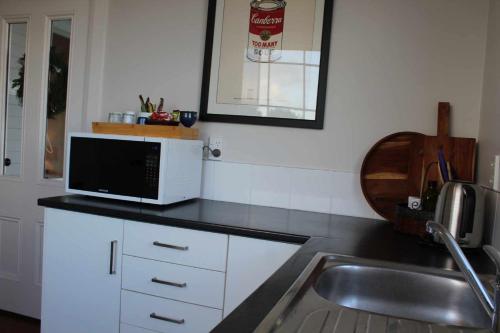 a kitchen with a sink and a microwave on a counter at The Suite - Huntly House in Auckland
