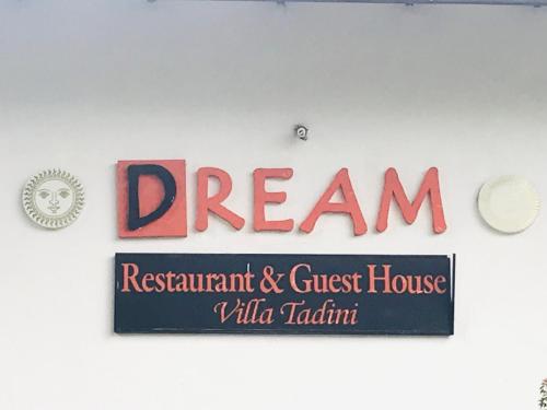 a sign for a restaurant and guest house on a wall at Villa tadini in Galle