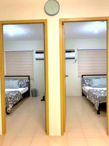 a room with two beds and a clock on the wall at B2B Condo, MARINA SPATIAL - Dumaguete in Dumaguete