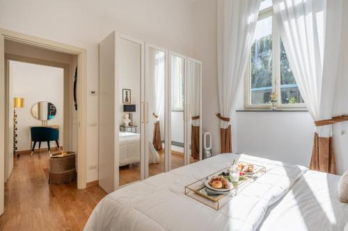 a white bedroom with a tray of fruit on a bed at Maison Mirò with private parking in Lucca