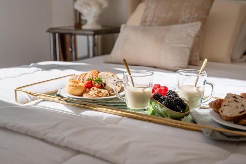 a tray of breakfast foods on a bed with milk at Maison Mirò with private parking in Lucca