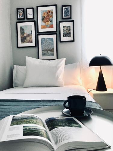 Una cama con un libro y una taza sobre una mesa en Apartamentos Élite - Art Collection - Vincent, en Mérida