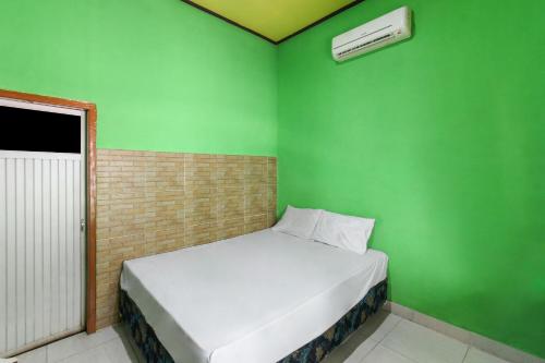mały zielony pokój z łóżkiem i zieloną ścianą w obiekcie OYO 92908 Hotel Jayanni w mieście Labu Sumbawa