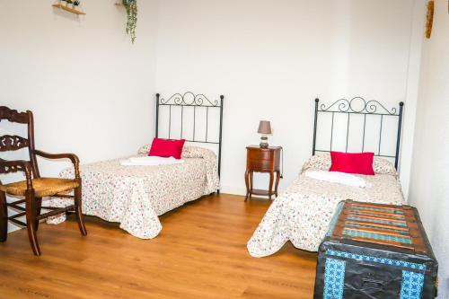 Zimmer mit 2 Betten mit roten Kissen und einem Stuhl in der Unterkunft El Patio de los Naranjos in Guadalupe