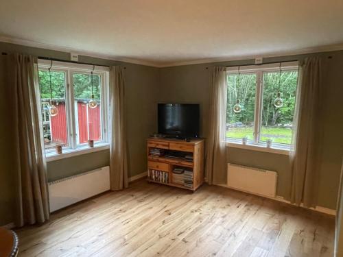 a living room with two windows and a television at Torp ved Mårbacka (Helt hus til leie) Östra Ämtervik/ Sunne in Östra Ämtervik