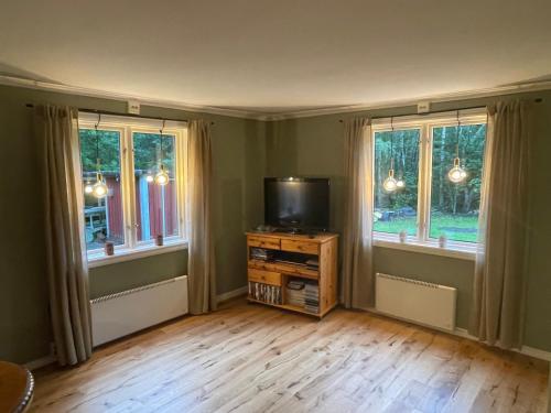 a living room with a tv and two windows at Torp ved Mårbacka (Helt hus til leie) Östra Ämtervik/ Sunne in Östra Ämtervik