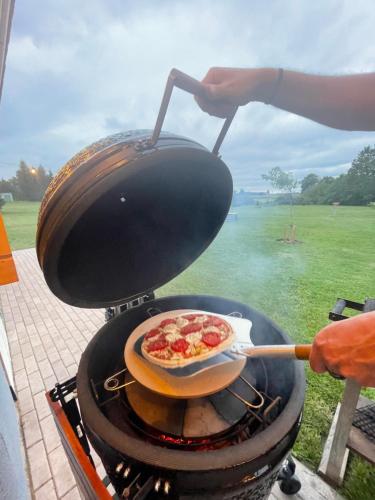 a person cooking a pizza on a grill at Karukella puhkemaja in Lyuganuse