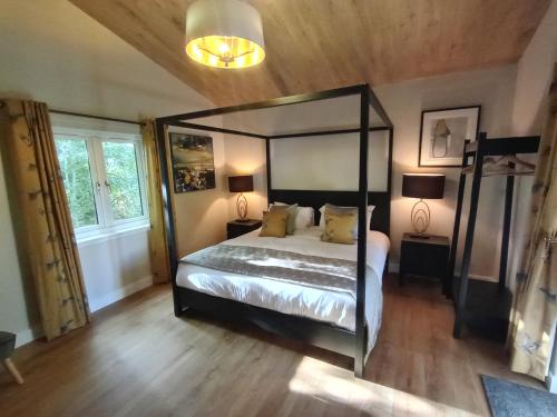 a bedroom with a canopy bed and two lamps at Breckland Lodge 1 with Hot Tub in Belladrum