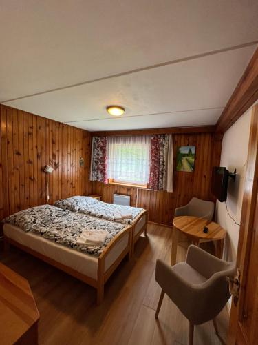 a bedroom with a bed and a table and a chair at Penzion Trampska Bouda in Abertamy