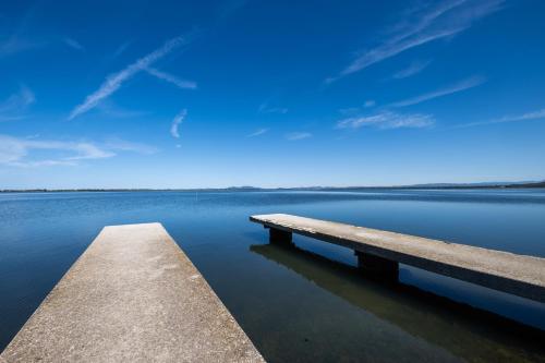 a pier on a body of water with a blue sky at Casa Vacanze Santa Clara in Orbetello