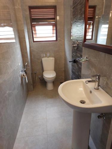 a bathroom with a white sink and a toilet at Mcleod-Inn in Kandy