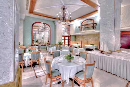 een eetkamer met tafels en stoelen en een kroonluchter bij Mediterranean Hotel in Rhodos-stad