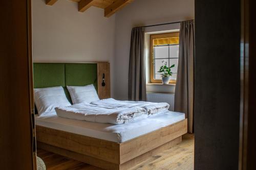 a bedroom with a bed with a green headboard and a window at Weinzeit Chalet & Appartements in Königsleiten