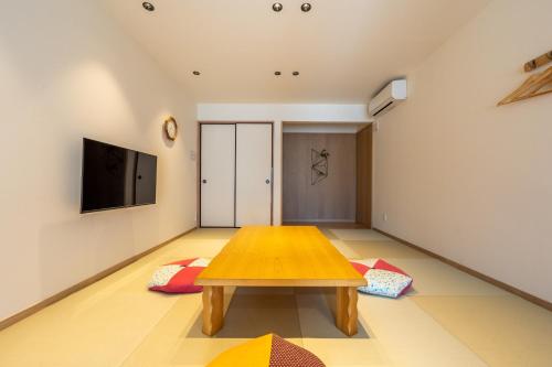 a living room with a wooden table and a flat screen tv at Irodori Hotel KITSUNE in Fukuoka