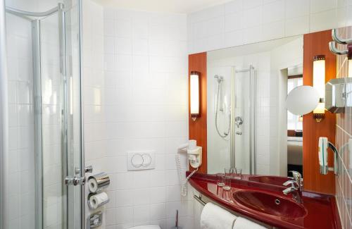 ein Bad mit einem roten Waschbecken und einer Dusche in der Unterkunft Leonardo Hotel Salzburg City Center in Salzburg