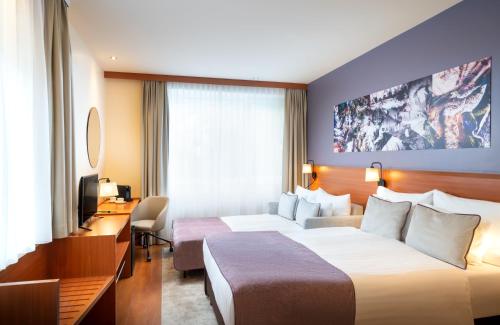 a hotel room with two beds and a desk at Leonardo Hotel Salzburg City Center in Salzburg