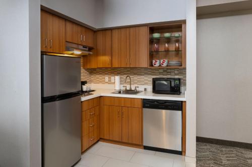 a kitchen with wooden cabinets and a stainless steel refrigerator at Springhill Suites by Marriott Anaheim Maingate in Anaheim