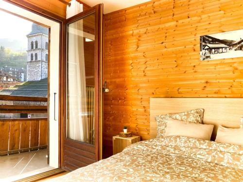 a bedroom with a bed and a wooden wall at Appartement au cœur de La Clusaz (50m des pistes) in La Clusaz