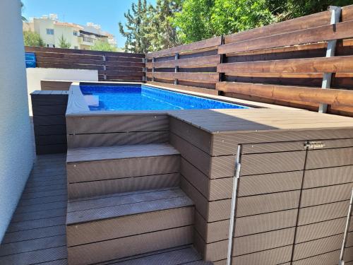 a swimming pool in a backyard with a wooden fence at ELeAN VILLA in Paphos City