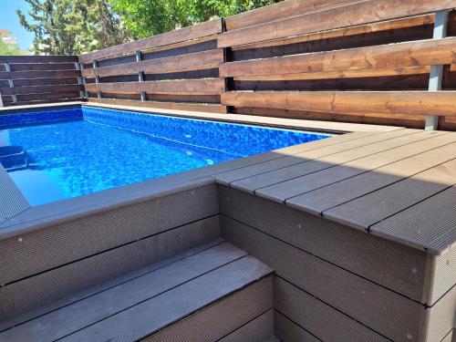 a swimming pool with a wooden retaining wall and a wooden deck at ELeAN VILLA in Paphos City