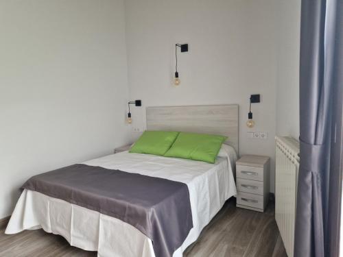 パネスにあるApartamentos Villa de Panes - La Plazaの白いベッドルーム(緑の枕とベッド付)