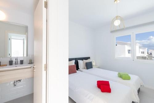 een slaapkamer met 2 bedden met rode en groene kussens bij Casa Lolalo - Modern Villa with pool, 15min walk to Marina Rubicón in Playa Blanca