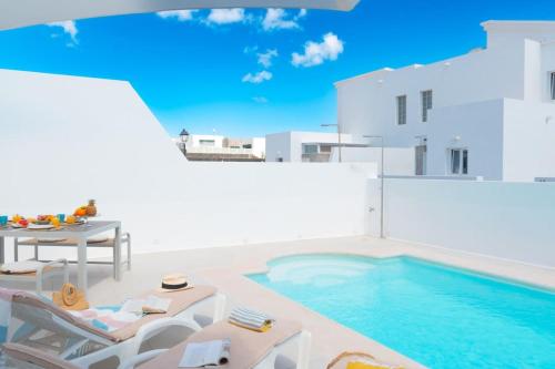 een zwembad met stoelen en een tafel en een zwembad bij Casa Lolalo - Modern Villa with pool, 15min walk to Marina Rubicón in Playa Blanca
