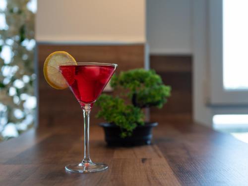 une boisson rouge dans un verre avec une tranche orange dans l'établissement LE CELESTE - HYPERCENTRE PARKING ET NETFLIX GRATUITS PROCHE TRAMWAY ET PARC DE LA TETE D'OR, à Villeurbanne