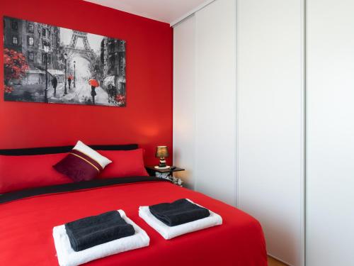 Un dormitorio rojo con una cama roja con dos toallas. en LE CELESTE - HYPERCENTRE PARKING ET NETFLIX GRATUITS PROCHE TRAMWAY ET PARC DE LA TETE D'OR, en Villeurbanne