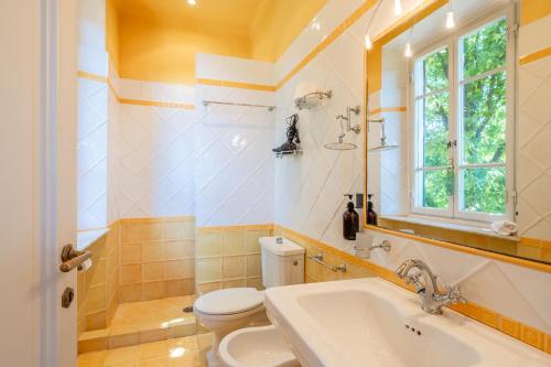 een badkamer met een wastafel, een toilet en een raam bij Villa Agnese Suites in Lucca