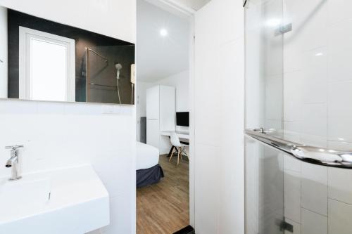 ein weißes Badezimmer mit einem Waschbecken und einem Spiegel in der Unterkunft Blu Monkey Bed & Breakfast Phuket - SHA Plus in Phuket