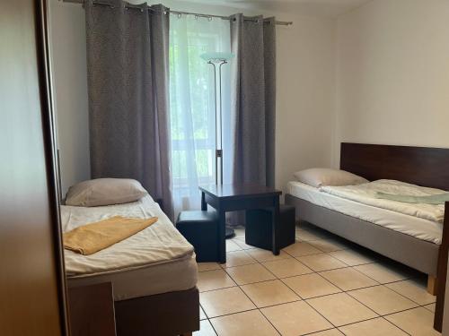 1 dormitorio con 2 camas, mesa y ventana en Motel w Łące, en Bolesławiec