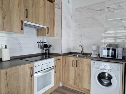 a kitchen with wooden cabinets and a washing machine at Apartamentos Villa de Panes - San Roque in Panes