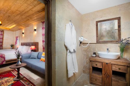 ein Bad mit einem Waschbecken und ein Bett in einem Zimmer in der Unterkunft Cappadocia Pyramid Stone House in Uchisar